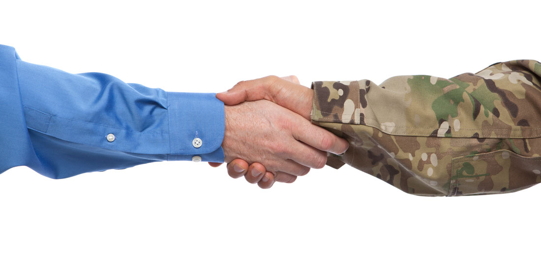 A businessman and a man in military uniform shaking hands.