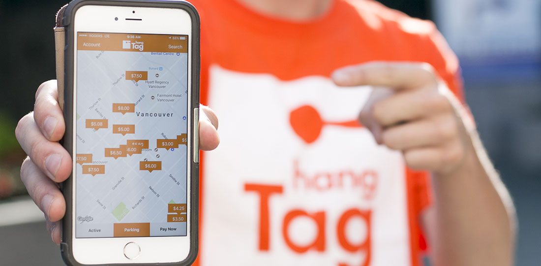 A man wearing a hangTag shirt points to a smartphone depicting hangTag's interactive map.
