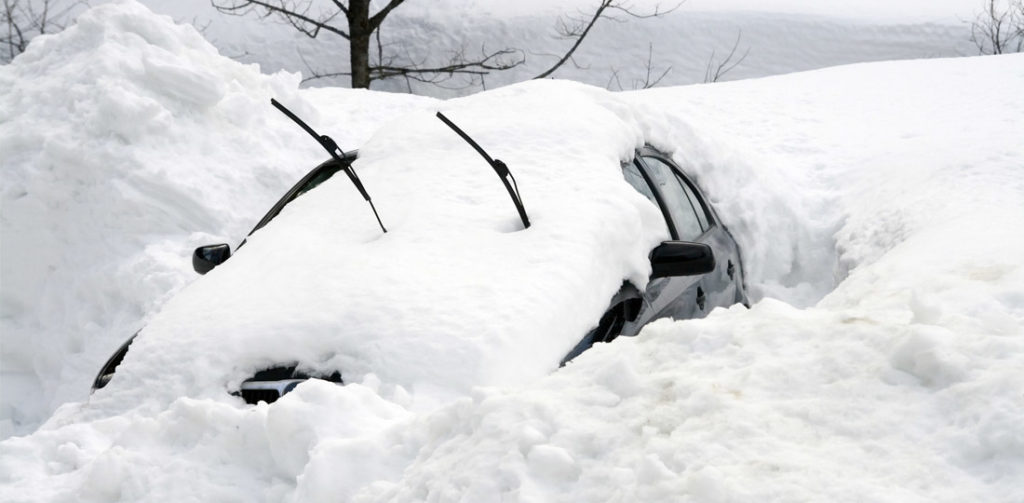 A parked car is barely visible under a mound of snow.