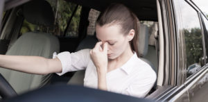 Une conductrice tenant son index et son pouce contre sa tête en signe de frustration et d'inconfort.